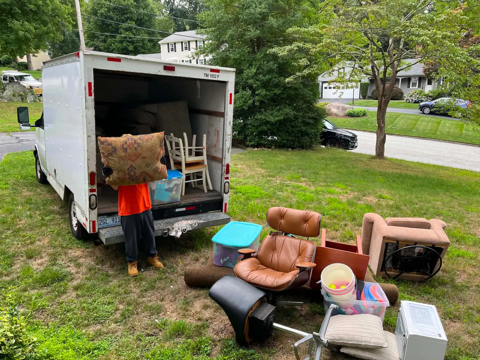 Junk removal crew loading a sofa into a dump truck at a Rhode Island home